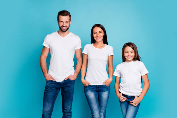 porträt der charmanten familie trägt weiße jeans mit zu schüchternem lächeln isoliert über blauem hintergrund - offspring child toothy smile beautiful stock-fotos und bilder