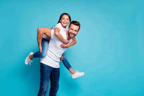 porträt von fröhlichen menschen lachen schweinchen tragen weiße t-shirt jeans isoliert über blauem hintergrund - vater stock-fotos und bilder