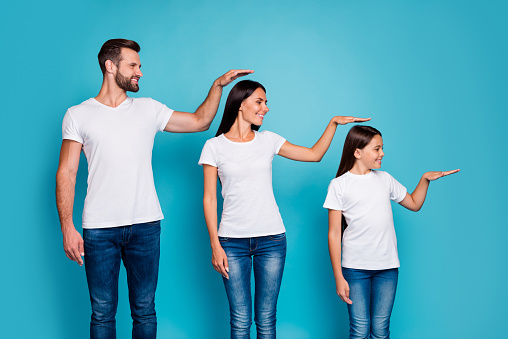 Profile side photo of sweet parent and their daughter with brunet hair holding, hand looking wearing white t-shirt denim jeans isolated over blue background