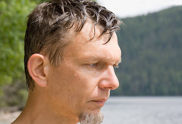 A 35-40-year-old tourist in a black jacket and sunglasses looks thoughtfully into the distance against the background of the landscape.