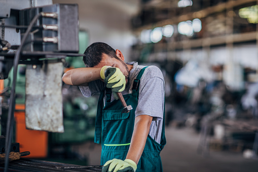 One man, young man working on a machine in factory workshop alone.