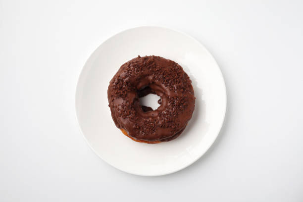 istock chocolate frosted doughnut on plate isolated on white background 1175702687