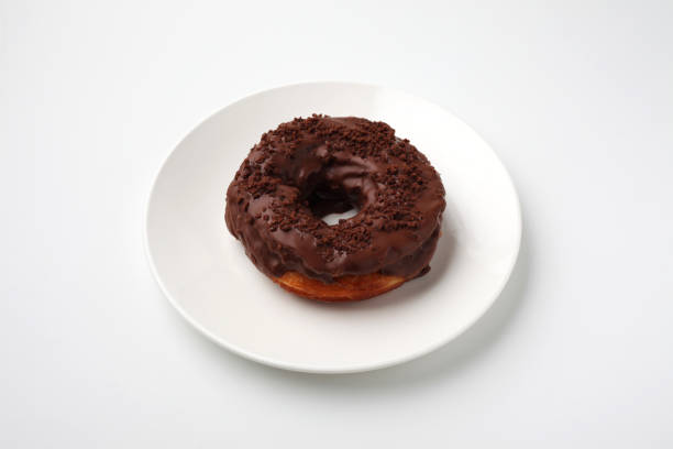 istock chocolate frosted doughnut on plate isolated on white background 1175703287