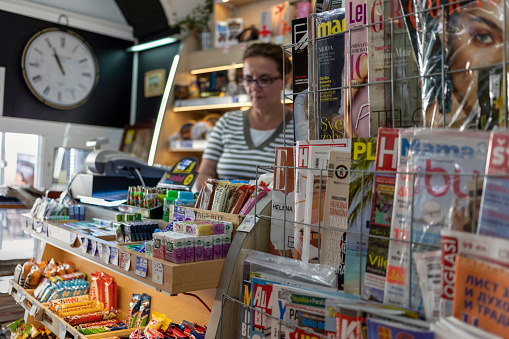 Belgrade, Serbia, June 16th 2019: Magazine stand and female seller in a tobacco shop in Zemun.