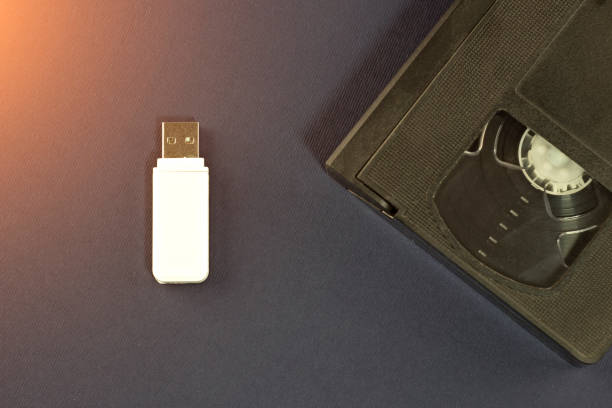 un lecteur de flash blanc sur un fond bleu et une cassette vidéo - usb flash drive sharing usb cable data photos et images de collection