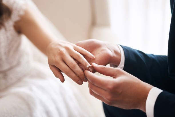 My heart is, and always will be, yours Cropped shot of an unrecognizable groom putting a diamond ring on his wife's finger during their wedding dinner jacket stock pictures, royalty-free photos & images
