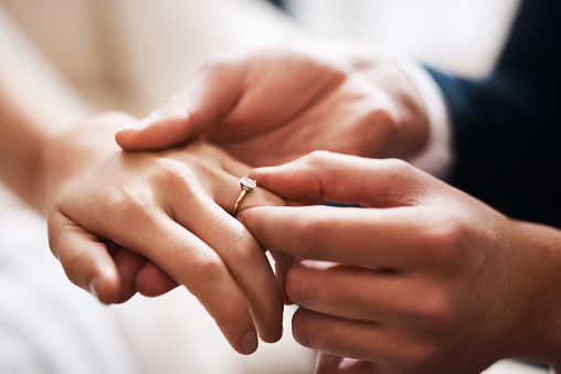 At the wedding ceremony, the bride puts the wedding ring on the groom's finger. Hands of newlyweds with wedding rings close-up. Heterosexual young couple in love at the moment of the wedding ceremony