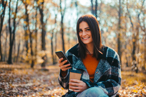 istock Happy woman using smartphone on beautiful autumn day in forest 1175710180