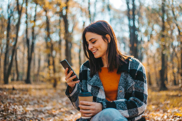 istock Happy woman using smartphone on beautiful autumn day in forest 1175710434