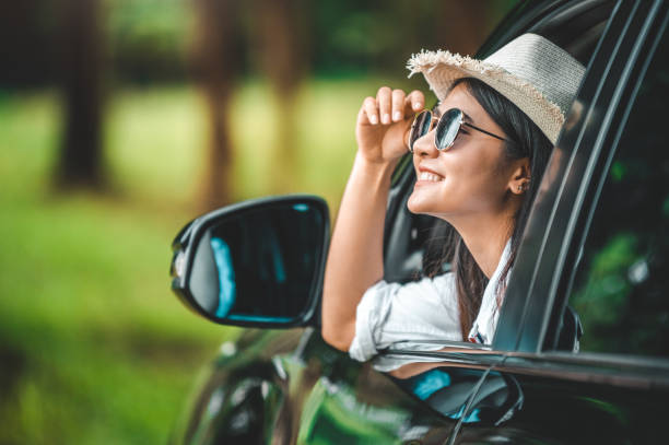 牧草地と山の湖の背景を持つオープンウィンドウカーの外に帽子を保持する幸せな女性の手。休暇中のロードトリップで旅行者としてリラックスした人々のライフスタイル。交通・旅行の概� - nature smiling teenage girls female ストックフォトと画像