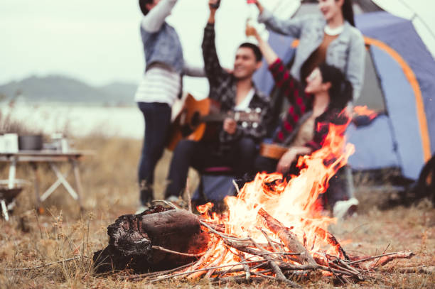 Closeup of bonfire and friendship clinking drinking bottle glass for celebrating in party with mountain meadow and lake view background. People lifestyle and travel vacation. Picnic and camping tent Closeup of bonfire and friendship clinking drinking bottle glass for celebrating in party with mountain meadow and lake view background. People lifestyle and travel vacation. Picnic and camping tent family bbq beach stock pictures, royalty-free photos & images