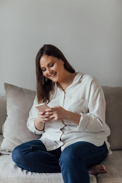 istock Woman Sitting on Couch and Using Cell Phone 1175717119