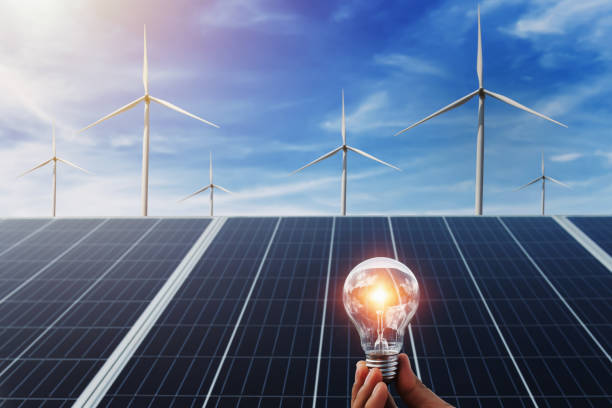 istock hand holding lightbulb with solar panel and wind turbine background. clean energy in nature concept 1175717760