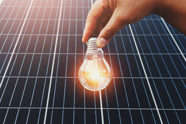 istock hand holding lightbulb with solar panel background. clean energy in nature concept 1175717777