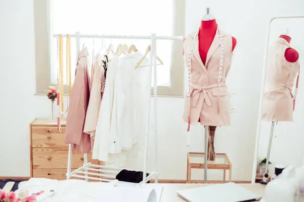 Fashion designer showroom studio workshop background with new collection of pink pastel female clothing design. Tailor and sewing concept. Dressmaker modern room interior red with mannequin