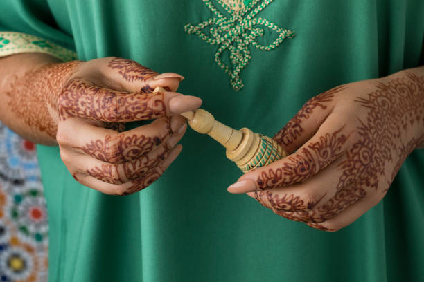 Moroccan woman with traditional henna painted hands holding a wooden kohl applicator