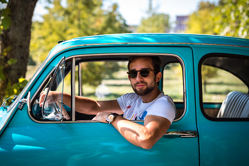 Man siting in vintage car on the road