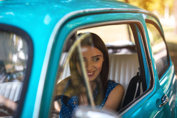 istock Smiling woman getting out from retro car 1175728154