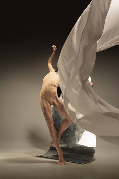 istock Young and stylish modern ballet dancer on brown background 1175729155