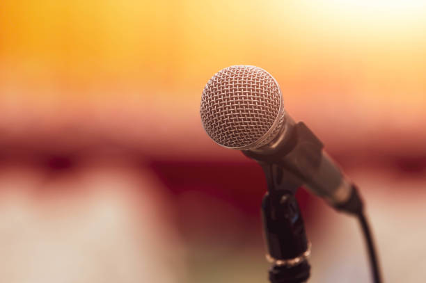 primer plano del micrófono sobre el discurso abstracto de fondo borroso en la sala de la sala de convenciones de seminarios y la luz como invitado y orador de conferencias en el podio. evento de taller y concepto de transmisión de entretenimiento. - contar fotografías e imágenes de stock