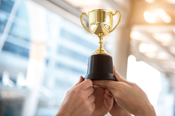 trofeo d'oro campione per il vincitore con le mani dei giocatori sportivi sullo sfondo dello stadio sportivo. concetto di successo e realizzazione. tema premio sport e coppa. premio di football americano e premio per il gioco di partite - cerimonia di premiazione foto e immagini stock