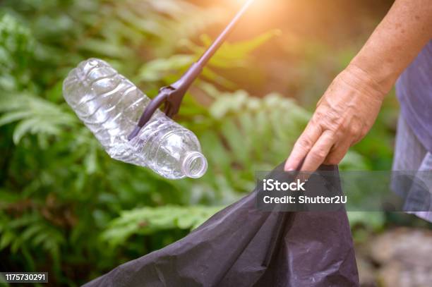 Closeup Of Hand And Waste Grabber Picking Up Drinking Plastic Bottle Waste Into Bag Ecology And Environmental Concerns Recycling Waste Reduction Techniques Ecofriendly Earth World Disaster Relief Stock Photo - Download Image Now
