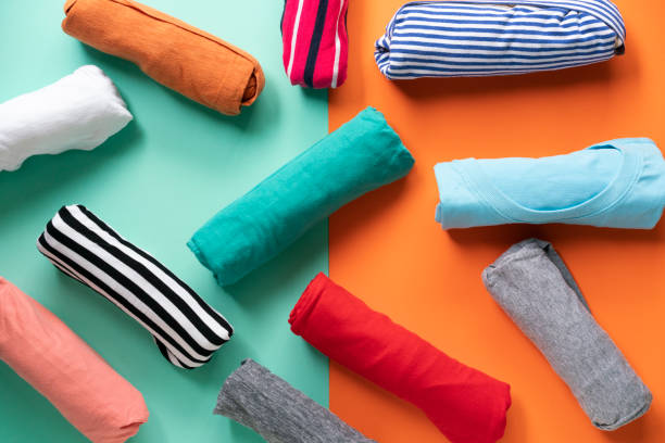 close up of rolled colorful clothes on color background close up of rolled colorful clothes on color background top garment stock pictures, royalty-free photos & images