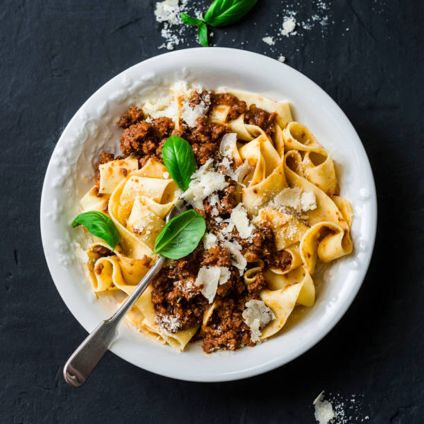 pasta pappardelle de frescura casera con salsa boloñesa de ternera sobre un fondo oscuro - pappardelle fotografías e imágenes de stock