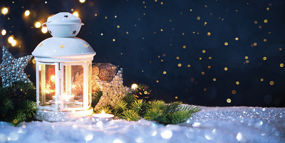 Burning lantern in the snow at night. Merry Christmas and Happy New Year card with copy space for your text.