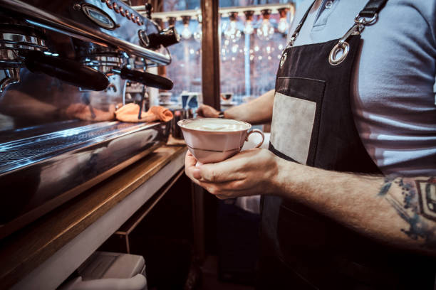 Barista holding a cup with an aromatic cappuccino in a cafe