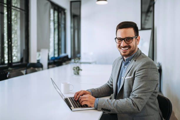 istock Confident handsome businessman sitting at office desk and smiling 1175740036