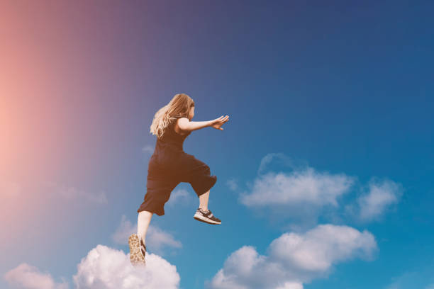 istock Cute girl jumping funny in clouds 1175742601