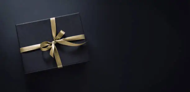 Photo of Gift wrapped in dark paper on dark background