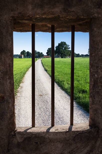 Dream of Freedom View from a Dark Medieaval Prison Cell, Outside a Gravel Road Can be Seen. dungeon medieval prison prison cell stock pictures, royalty-free photos & images