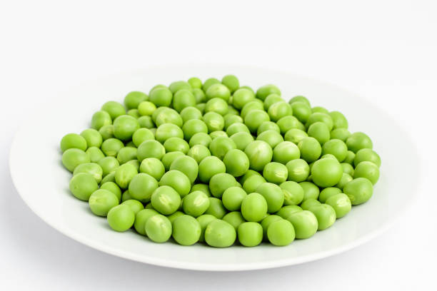 istock Fresh organic green peas on a white plate isolated on white, side view 1175749838