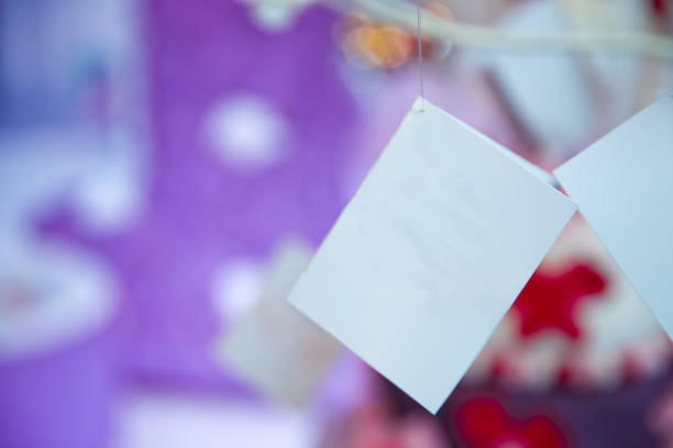 istock Blank card hanging on string with peg . A sheet of paper on a rope with clothespins on a blurred background .white note . White envelope and beige card hanging on string isolated on blure background . 1175749982