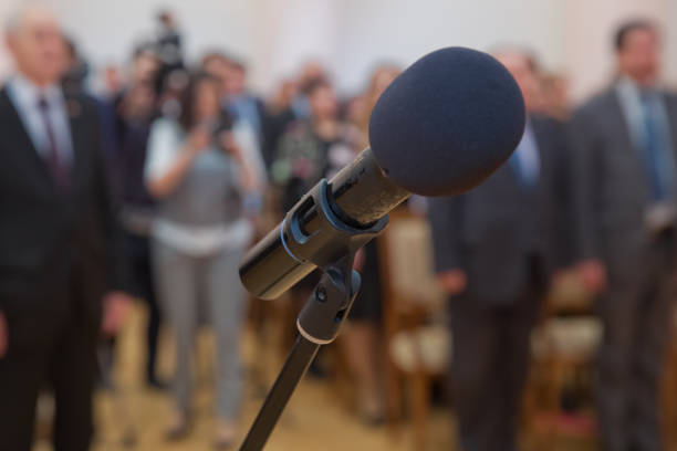 istock Wired microphone set up on the front of conference room close up with blurred background. Wired microphone close up with copy space . Close up of microphone in concert hall or conference room . 1175752693