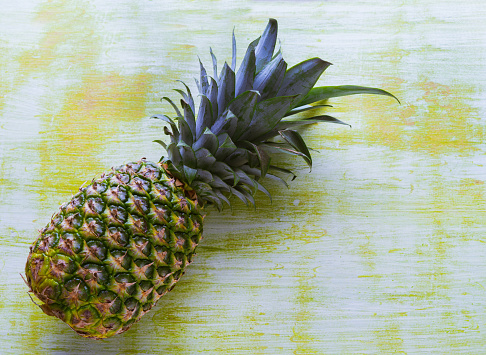 Whole pineapple on greenish wooden background. Copy space.