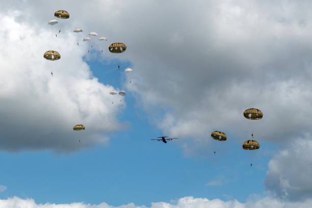 Dropping of paratroopers by a Hercules airplane at the occasion of the 75th anniversary of operation Market Garden during World War II This photo was taken at the 75th anniversary of the dropping of para troops in Groesbeek. That happened on September 17, 1944 in the context of Operation Market Garden. In a few days, almost 8,000 American paratroopers were dropped in the immediate surroundings of Groesbeek. In the first days after September 17, the surroundings of Groesbeek and Nijmegen changed into a hellish front area. The bridges of Nijmegen were conquered intact, but had to be defended against all German attacks in the following days and weeks. The Rhine bridge near Arnhem eventually had to be abandoned by the English paratroopers. Large parts of the area south of Nijmegen were freed. This was of great strategic importance for the course of the war; from here the Rhineland offensive, the attack on the German flank, could be deployed. operation market garden stock pictures, royalty-free photos & images