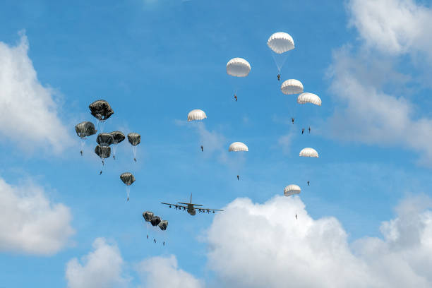 Dropping of paratroopers by a Hercules airplane at the occasion of the 75th anniversary of operation Market Garden during World War II This photo was taken at the 75th anniversary of the dropping of para troops in Groesbeek. That happened on September 17, 1944 in the context of Operation Market Garden. In a few days, almost 8,000 American paratroopers were dropped in the immediate surroundings of Groesbeek. In the first days after September 17, the surroundings of Groesbeek and Nijmegen changed into a hellish front area. The bridges of Nijmegen were conquered intact, but had to be defended against all German attacks in the following days and weeks. The Rhine bridge near Arnhem eventually had to be abandoned by the English paratroopers. Large parts of the area south of Nijmegen were freed. This was of great strategic importance for the course of the war; from here the Rhineland offensive, the attack on the German flank, could be deployed. operation market garden stock pictures, royalty-free photos & images