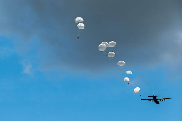 A Hercules airplane drops paratroopers at the occasion of the 75th anniversary of operation Market Garden during World War II This photo was taken at the 75th anniversary of the dropping of para troops in Groesbeek. That happened on September 17, 1944 in the context of Operation Market Garden. In a few days, almost 8,000 American paratroopers were dropped in the immediate surroundings of Groesbeek. In the first days after September 17, the surroundings of Groesbeek and Nijmegen changed into a hellish front area. The bridges of Nijmegen were conquered intact, but had to be defended against all German attacks in the following days and weeks. The Rhine bridge near Arnhem eventually had to be abandoned by the English paratroopers. Large parts of the area south of Nijmegen were freed. This was of great strategic importance for the course of the war; from here the Rhineland offensive, the attack on the German flank, could be deployed. operation market garden stock pictures, royalty-free photos & images