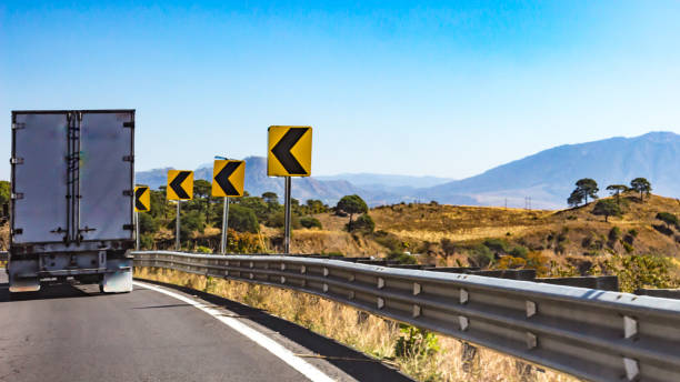 truck driving on a road with dangerous curve signage - wadi warning imagens e fotografias de stock