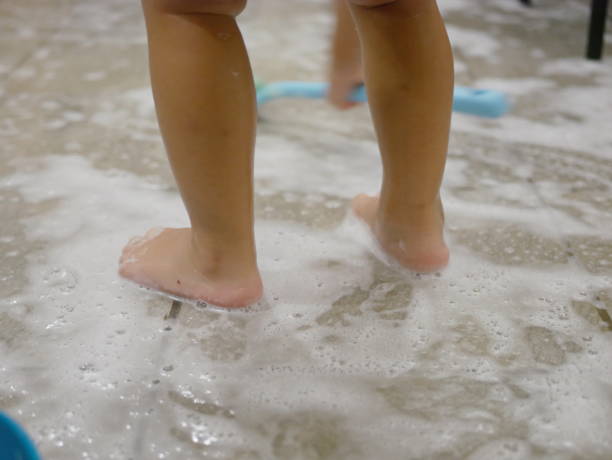 istock White foam and air bubbles at baby's feet on the bathroom floor, as she is haveing fun learning to clean a restroom - children development through allowing them to do housework 1175772784