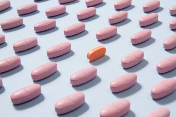 rosa pillen auf blauem hintergrund - pink pill stock-fotos und bilder