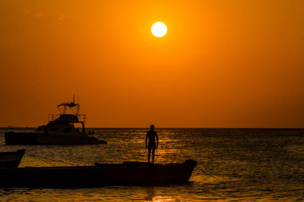 The sun sets with a man on a boat in Zanzibar, Tanzania