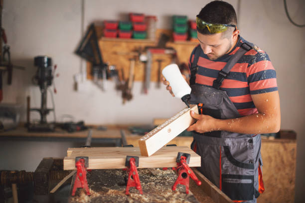 istock Young carpenter gluing wood 1175782273