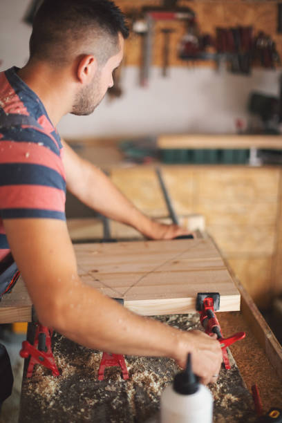 istock Young carpenter gluing wood 1175782552
