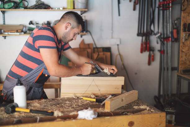 istock Young carpenter plaining wooden table 1175783440