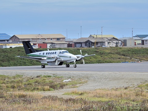 Nome airport and cityscape with a twin engine aircraft taxiing for takeoff