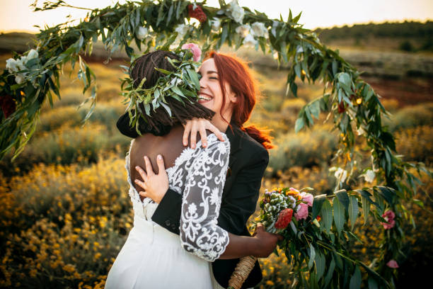 Wedding kiss Lesbian wedding ceremony. Two brides standing in a front of a wedding arch, kissing each other gay wedding kiss stock pictures, royalty-free photos & images